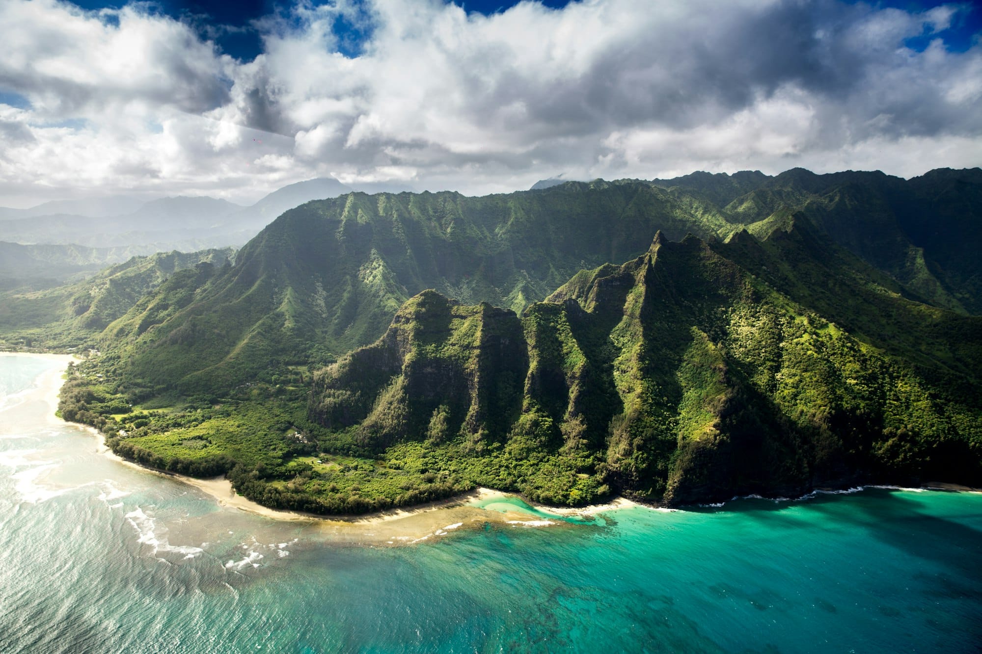 Green volcanic ridges meeting turquoise water along a Pacific coastline