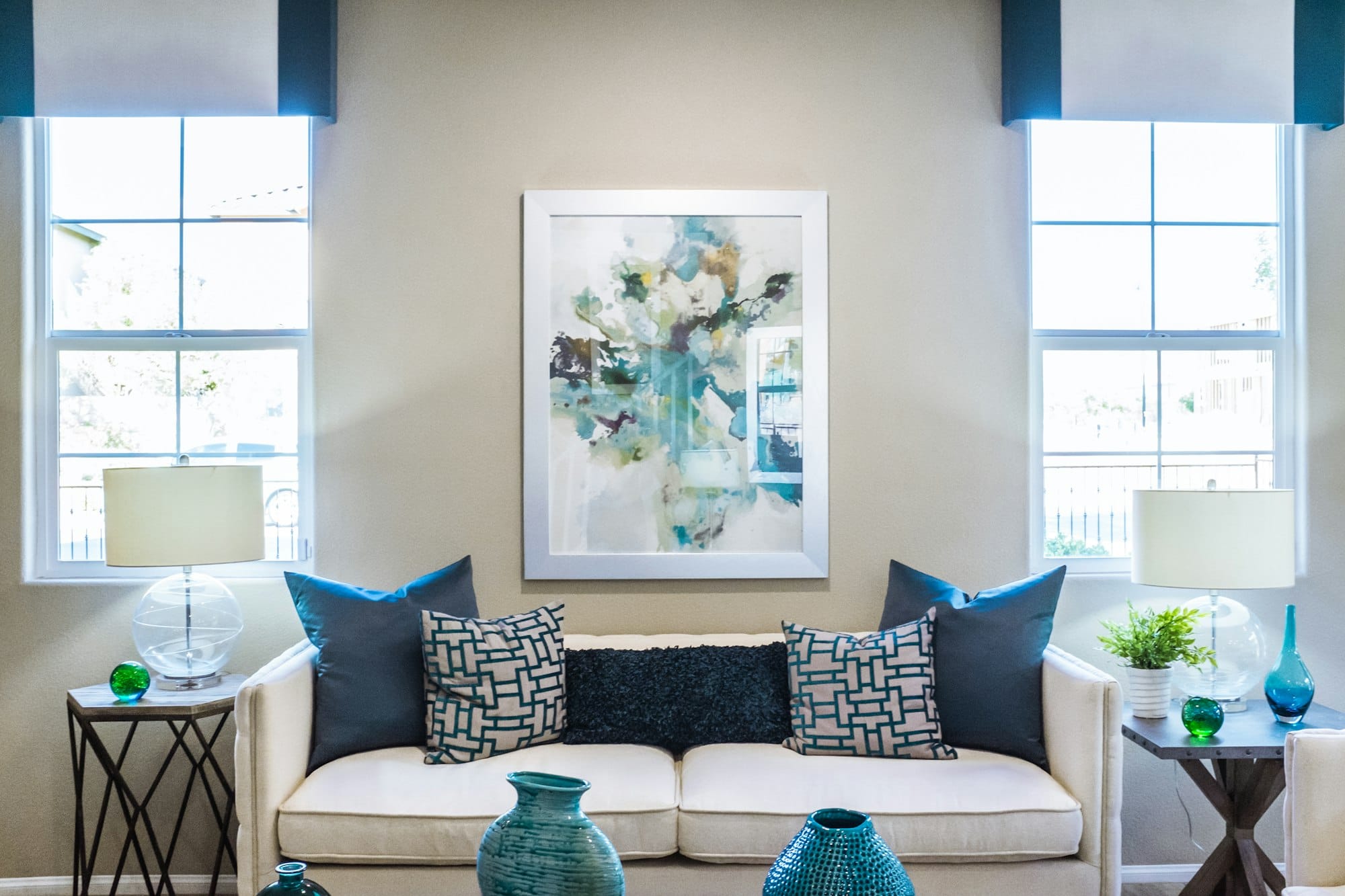 A bright living room with a cream sofa between two tall windows